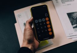 A phone calculator set to 0 on top of a stack of bills indicating unpaid debt.
