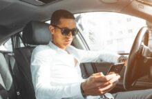 A man wearing sunglasses drives his car.