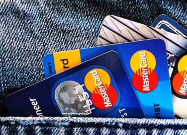 Four mastercard credit cards peek out of the pocket of a pair of jeans