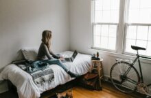 A woman sits on her bed in her room