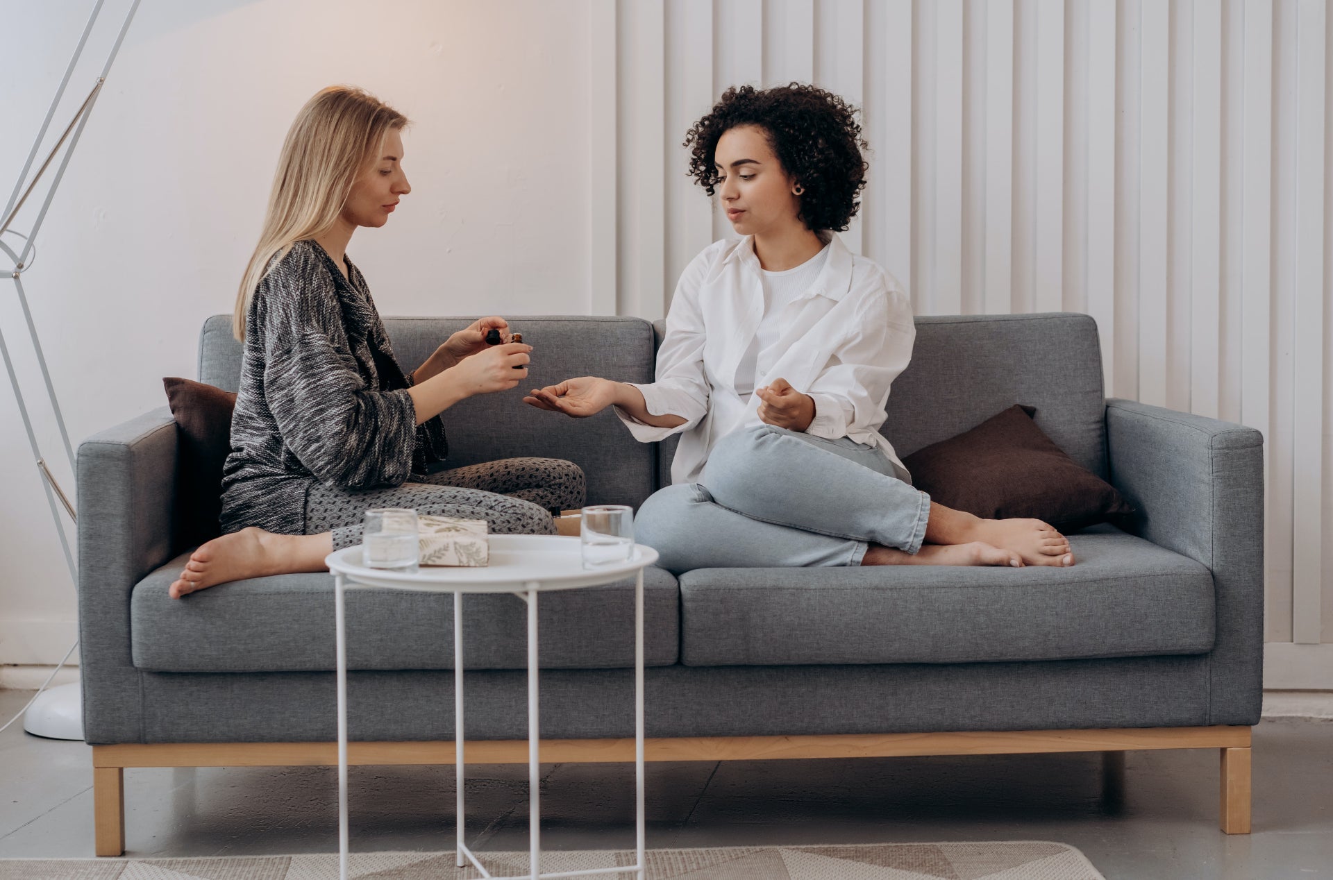 Two young women sit on the couch in their apartment discussing utility bill FAQs