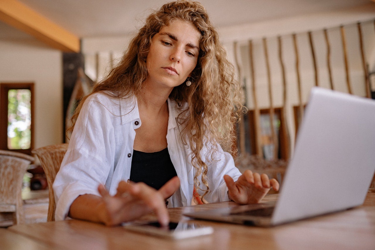 A woman at a laptop computer calculates how a 1099-C form will affect her taxes.
