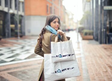 A woman goes shopping while holding shopping bags.