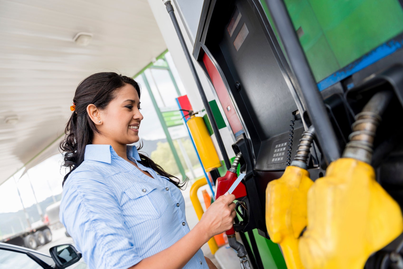Woman at the gas pump paying with gas credit cards