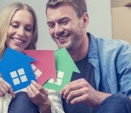 couple holding paper cut outs of houses happy because they are buying a house with bad credit