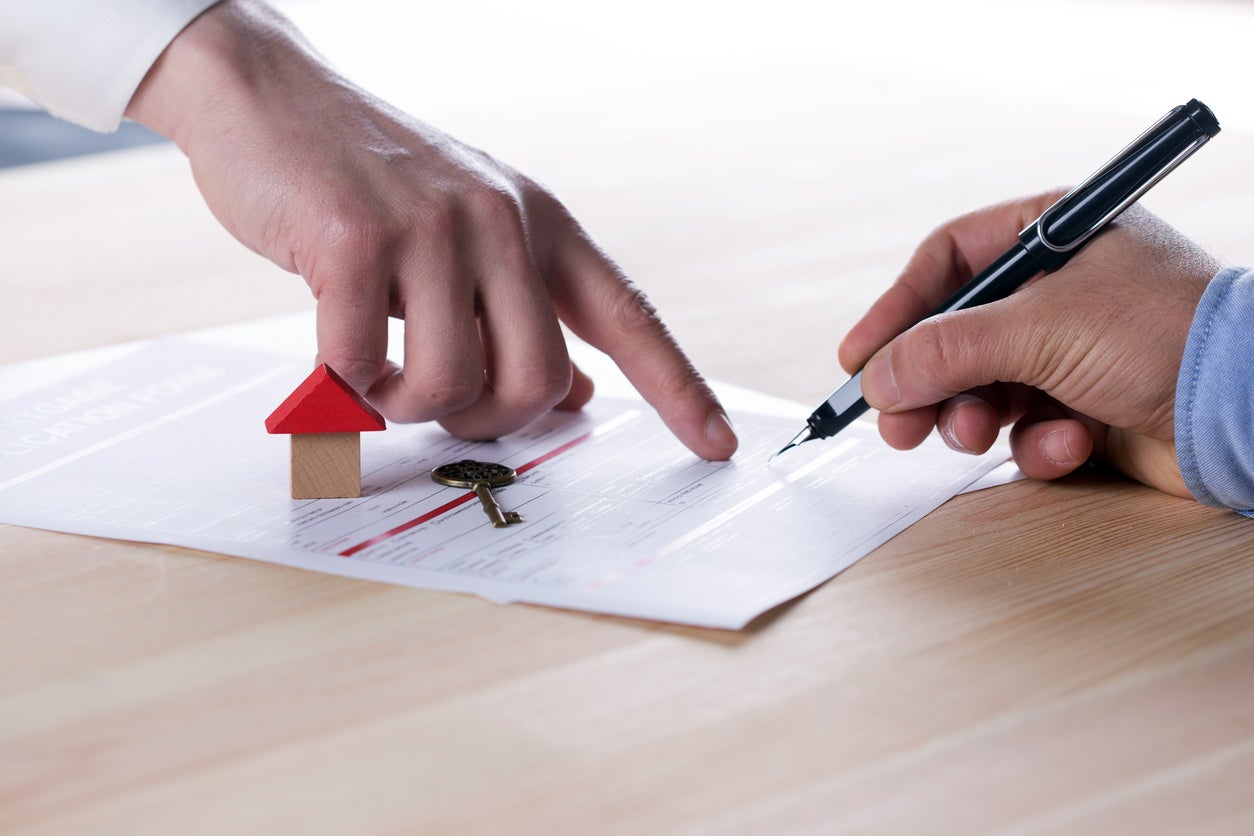 woman's hand pointing to paper work to show man holding pen how a mortgage works