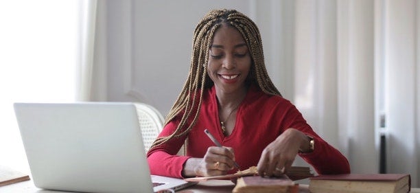 A woman sits at a table with her laptop in front of her.