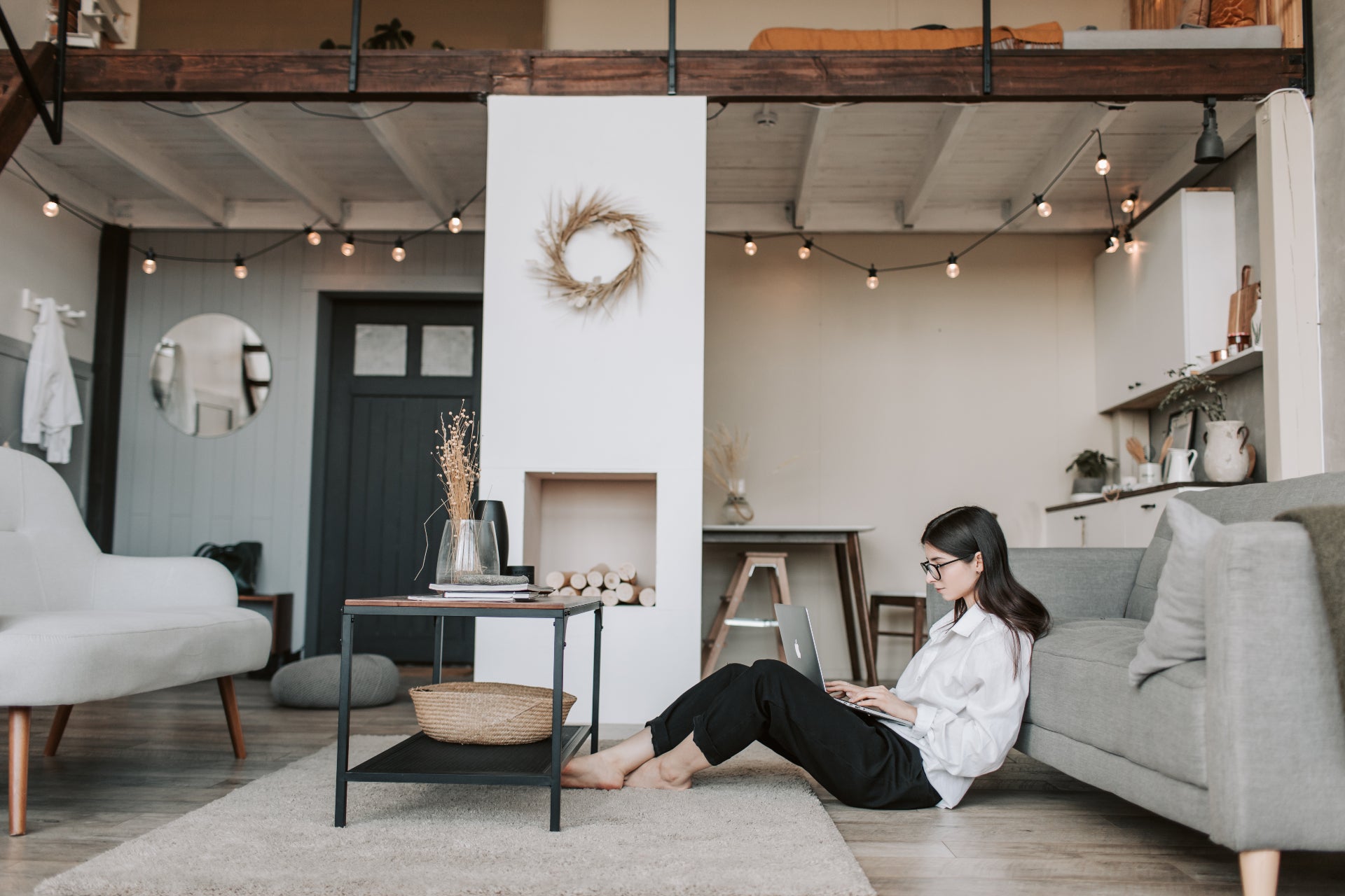 A woman sits on the floor in her living room on her laptop