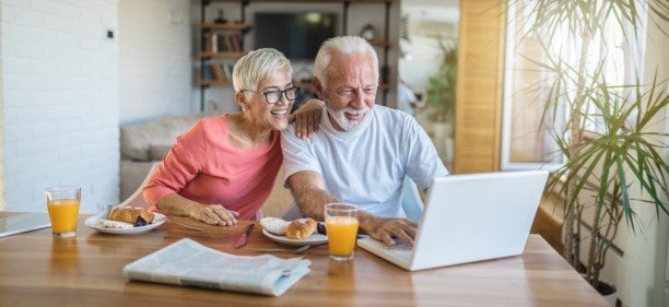 Senior couple looking at online savings account over breakfast
