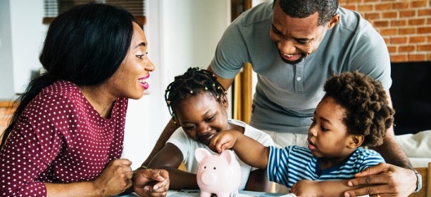 A family puts coins in a piggy bank as they discuss how to save money.