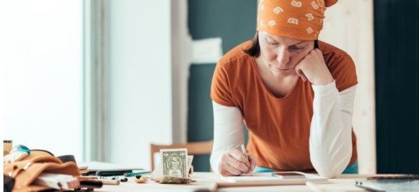 female carpenter at counter with money worrying about a payday loan