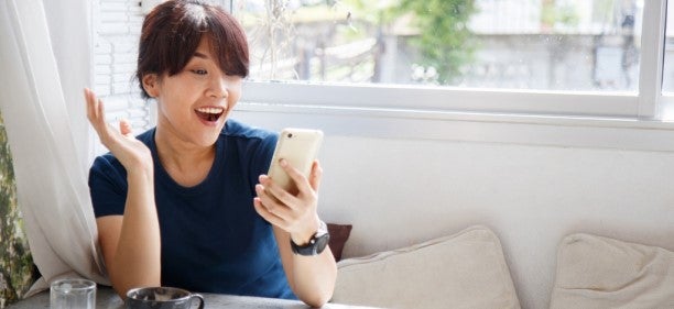 Happy young woman with phone who learned how to apply for a credit card online and got approved